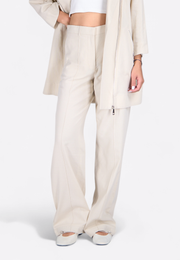 Close-up of high-waisted wide-leg beige trousers, worn by model – East Vibe